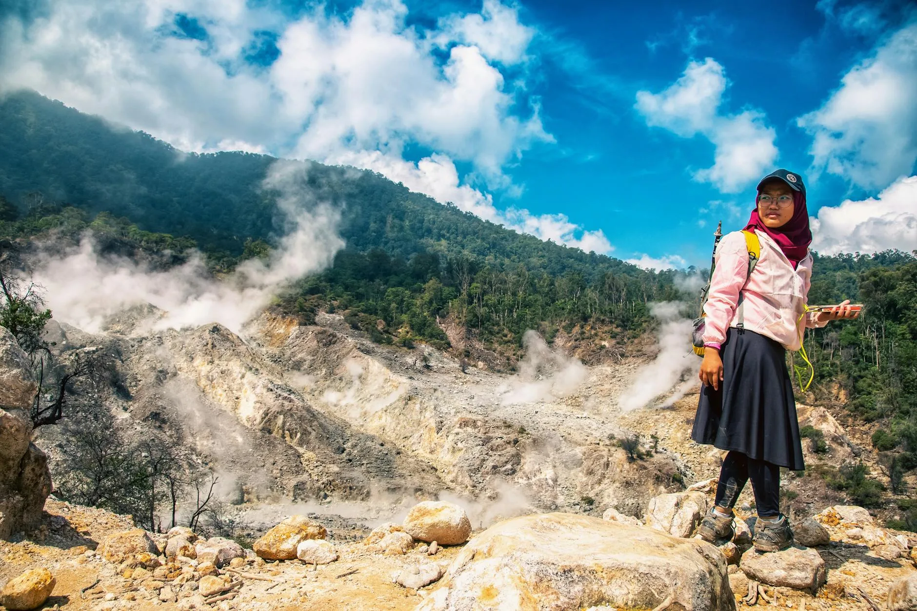 Kobieta przed dymiącym wulkanem na szlaku w słoneczny dzień