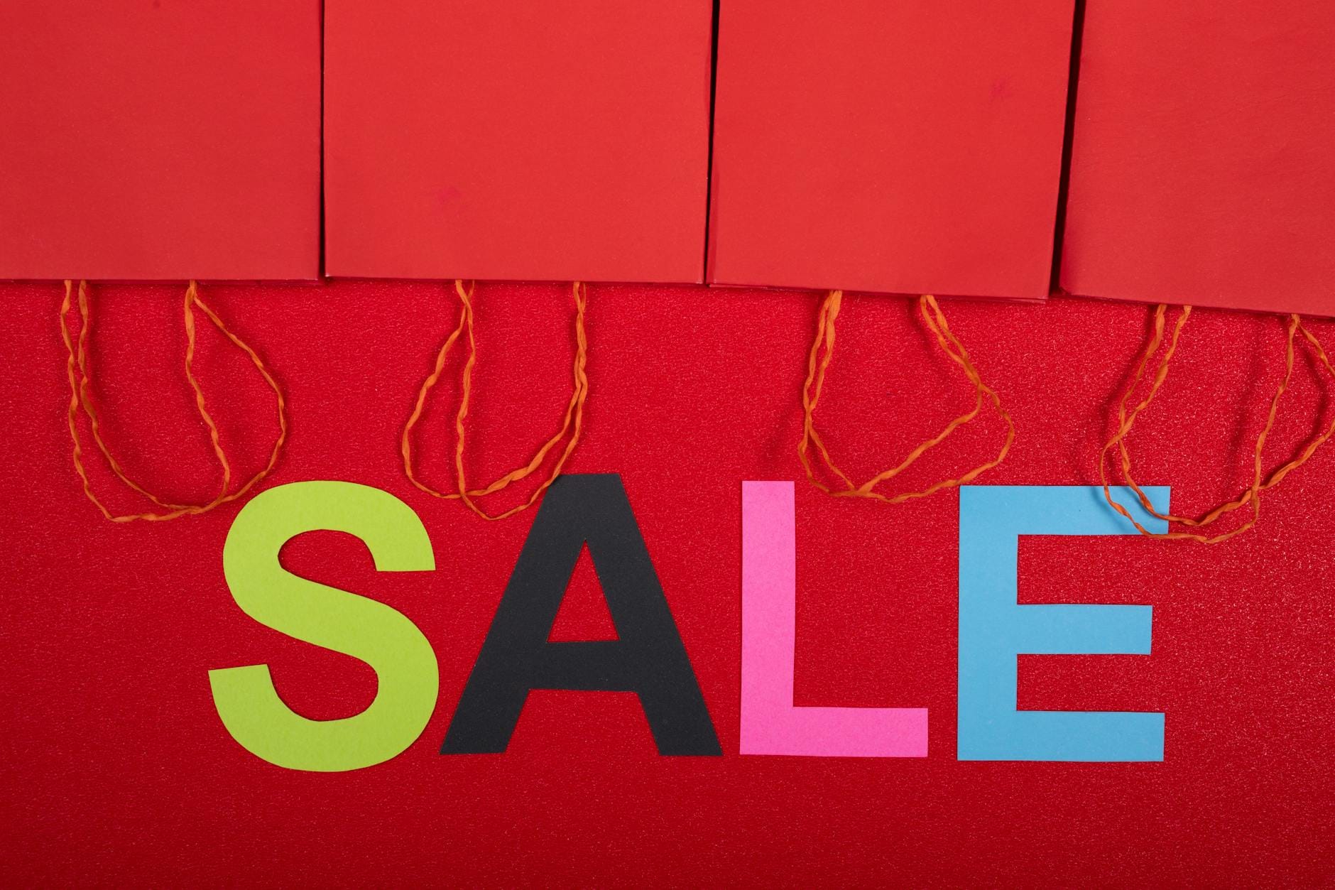 Kolorowy napis wyprzedaż z czerwonymi torbami zakupowymi w sklepie