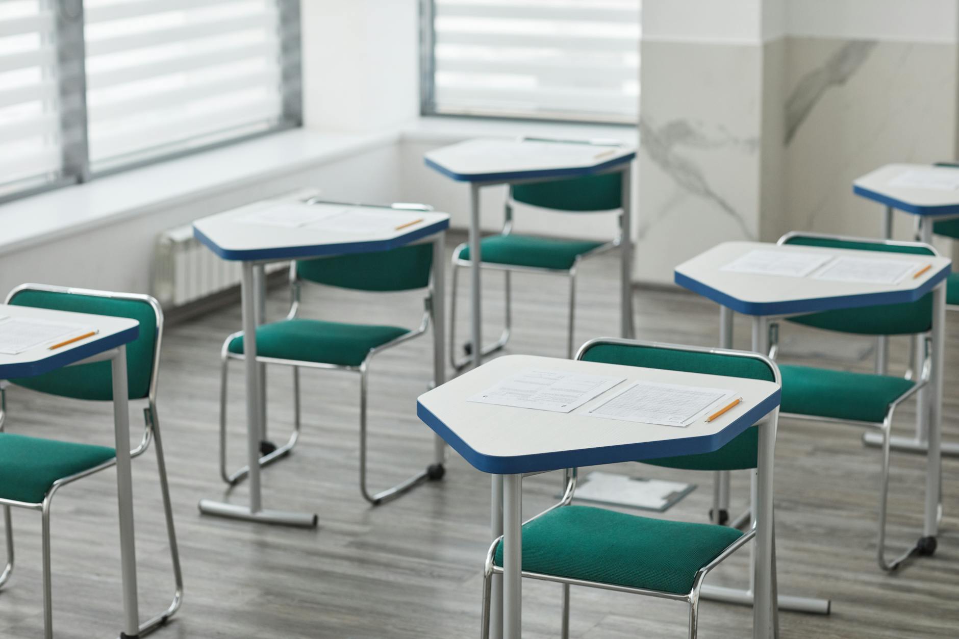 Pusta sala egzaminacyjna z ławkami, arkuszami testu i ołówkami
