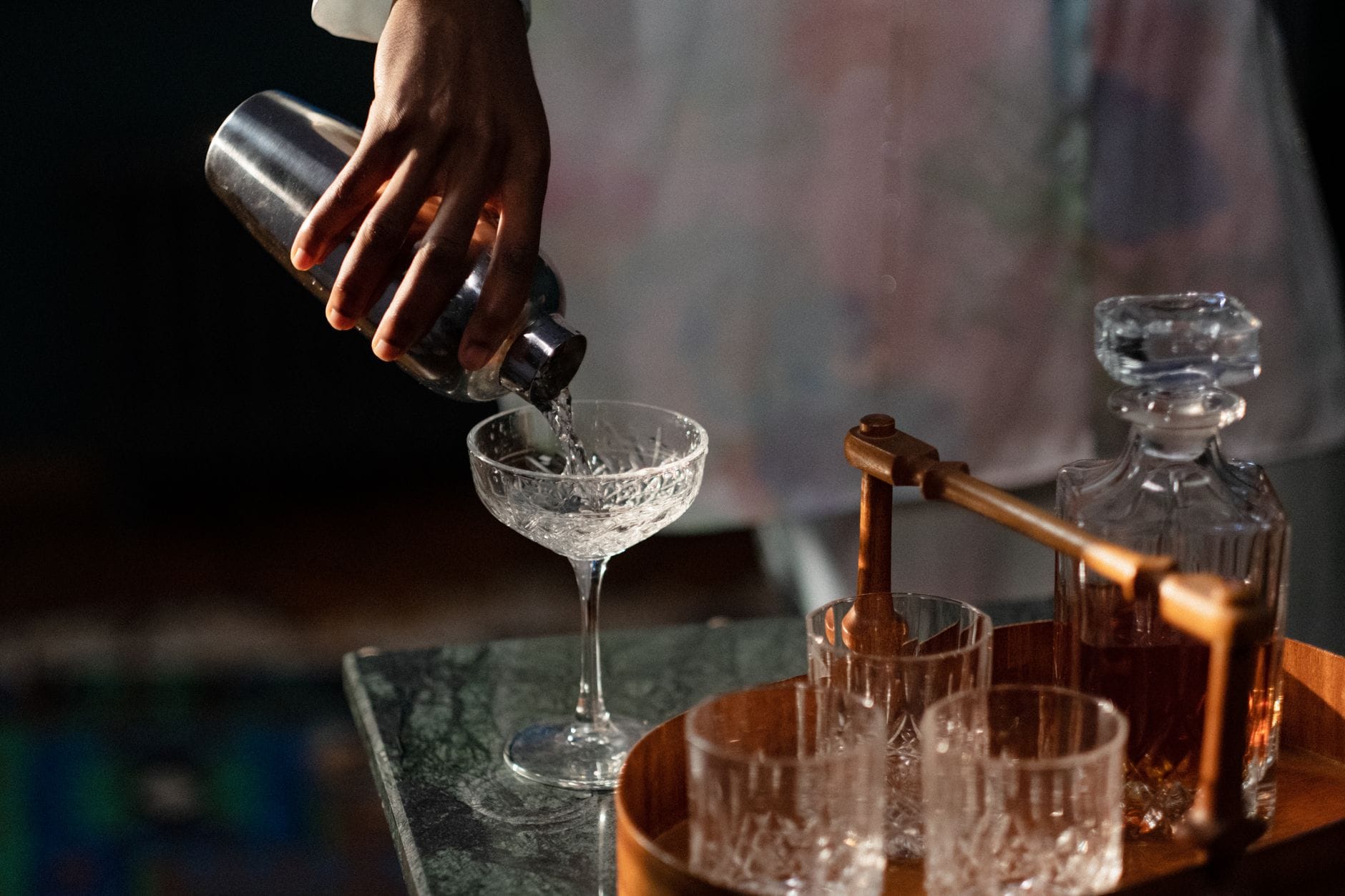 Barman przelewa drink z shakera do szklanki w domowym barze